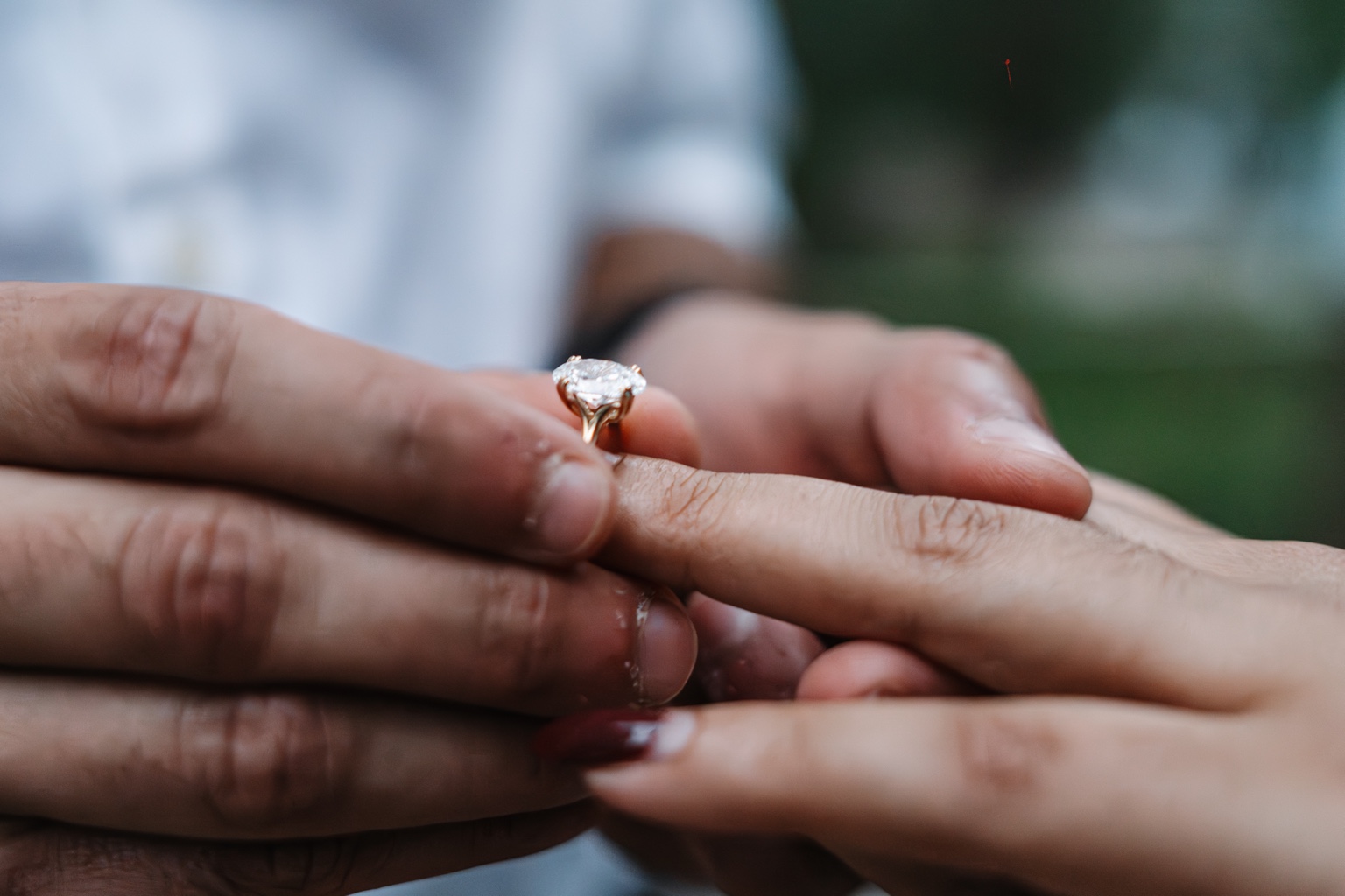 Close-up of Akhil’s hands holding Maggi’s hand as he slides the engagement ring onto her finger
